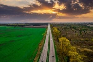 Lang vej gennem marker ved solnedgang