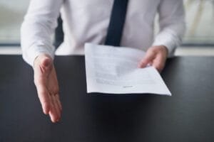 Person rækker hånd frem med kontrakt