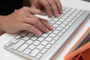 Hænder skriver på et hvidt tastatur