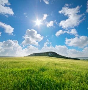 Solrig himmel over grøn mark og bakke