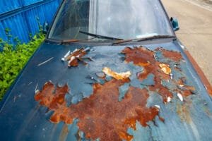 Bil med rusten og afskallet maling på motorhjelmen