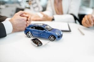 Bilkøbsaftale med blå modelbil og nøgler